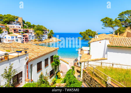 Case bianche con orange i tetti di tegole e i passaggi per la spiaggia di Sa Tuna la pesca costiera village, Costa Brava, Spagna Foto Stock