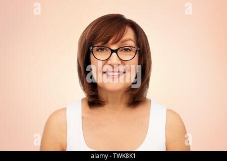 Ritratto di donna senior in bicchieri su bianco Foto Stock