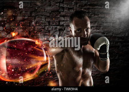 Fiducioso athletic boxer con fiery guantoni da pugilato Foto Stock