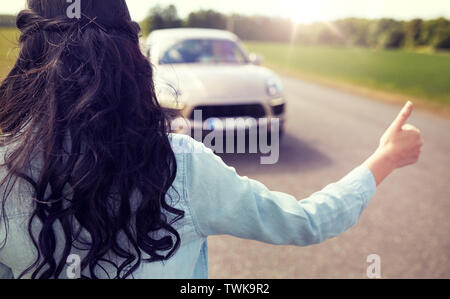 Donna autostop e arresto di auto con pollice in alto Foto Stock