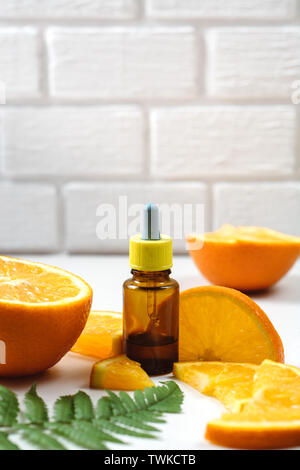 La vitamina C e la mesoterapia. Siero con vitamina C in bottiglie in vetro marrone, foglia di felce e arancio in un taglio. Alte dosi di vitamina C sintetica per la pelle. Organic Foto Stock