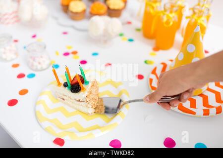 Mettendo mano pezzo di torta di compleanno su piastra Foto Stock