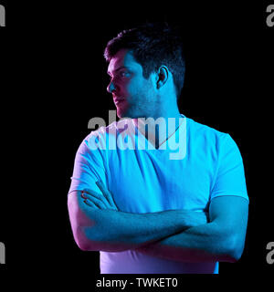 Uomo con bracci incrociati su luci al neon nelle tenebre Foto Stock