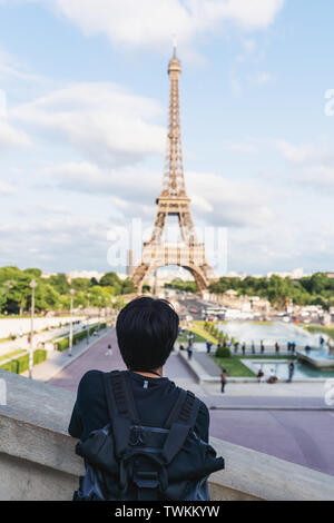 Un uomo con zaino guardando la torre Eiffel, famoso punto di riferimento e meta di viaggio a Parigi, Francia. Viaggiare in Europa in estate Foto Stock