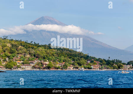 Vista del vulcano Agung dall'oceano. Villaggi, case tradizionali barche da pesca jukung intorno a. Amed, Karangasem Regency, Bali, Indonesia Foto Stock