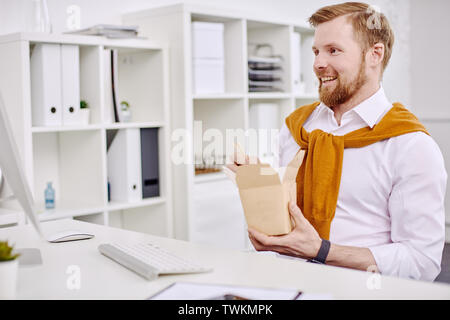 Età media imprenditore avente il pranzo presso il computer in ufficio Foto Stock