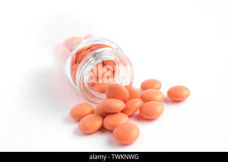 Le compresse di colore arancione dalla bottiglia di vetro su sfondo bianco copyspace per il testo. Epidemia, antidolorifici, healthcare, trattamento pillole e abuso di droga concetto. Foto Stock
