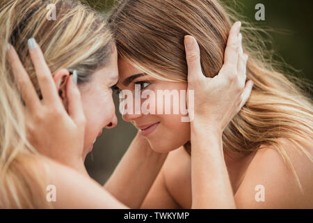 Una madre e figlia sono mantenendo le loro teste e guardando ogni altro. Foto Stock