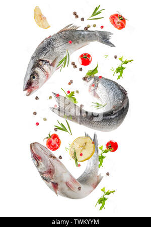 Materie spigola pesce con spezie e ingredienti, pronti per la cottura, con padella. Flying cibo isolare su sfondo bianco Foto Stock