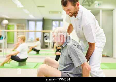 Fisioterapista dà assistenza senior con un esercizio di back school di Reha corso Foto Stock