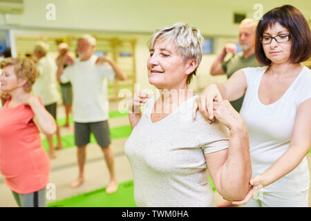 Fisioterapista dà donna senior di assistenza con un esercizio di indietro in fisioterapia Foto Stock