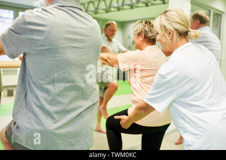 Fisioterapista dà dei cittadini anziani aiutare con la fisioterapia presso il balletto bar Foto Stock