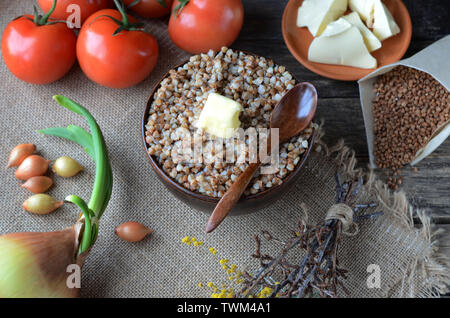 Farinata di grano saraceno con il burro in una ciotola di argilla su una tavola di legno Foto Stock