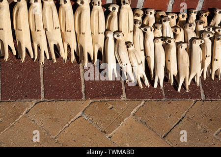 Figurine animali che assomigliano al meerkat scolpito di legno per la vendita come souvenir della fauna selvatica africana in un mercato locale di strada in Sudafrica. Foto Stock