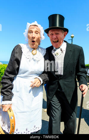 Broadstairs Dickens Festival. All'aperto, una donna senior house maid guardando scioccato e sorpreso come senior colleghi sorge accanto a lei e afferra il fondo in un po' scherzoso hanky panky. Foto Stock