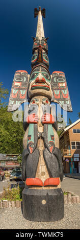 Sett. 17, 2018 - Ketchikan, AK: Tall panoramica della bellissima e molto alto Chief Johnson Totem Pole con chiaro cielo blu scuro e costruzioni locali. Foto Stock