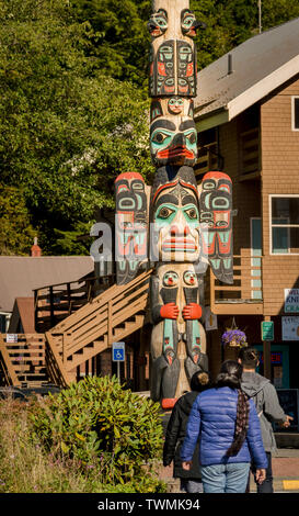 Sett. 17, 2018 - Ketchikan, AK: Tre turisti che indossa giacche visualizzazione Chief Johnson Totem sulla giornata soleggiata con costruzioni locali in background. Foto Stock