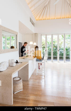 Coppia costituente il pranzo su un isola bianca cucina a casa Foto Stock