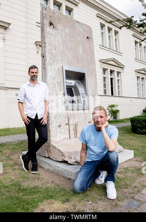 Berlino, Germania. Il 21 giugno, 2019. Michael Elmgreen (r) e Ingar Dragset, insieme i Danish-Norwegian duo di artisti Elmgreen e Dragset, sedersi di fronte al loro scultura 'Statue di liberta' nel cortile di Hamburger Bahnhof. La scultura da 2018 è costituito da un segmento di calcestruzzo del muro di Berlino in cui un functionless cash dispenser è integrato. Il lavoro è stato donato dal collettore Heiner Wemhöner e viene presentato come un permanente di sculture all'aperto. Credito: Christoph Soeder/dpa/Alamy Live News Foto Stock