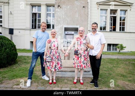 Berlino, Germania. Il 21 giugno, 2019. Michael Elmgreen (l) e Ingar Dragset (r), insieme all'artista Danish-Norwegian duo Elmgreen e Dragset, stand con l'artista giovane Eva & Adele (M) nella parte anteriore della loro scultura 'Statue di liberta' nel cortile di Hamburger Bahnhof. La scultura da 2018 è costituito da un segmento di calcestruzzo del muro di Berlino in cui un functionless cash dispenser è integrato. Il lavoro è stato donato dal collettore Heiner Wemhöner e viene presentato come un permanente di sculture all'aperto. Credito: Christoph Soeder/dpa/Alamy Live News Foto Stock