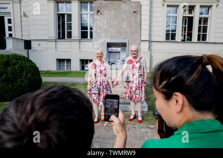 Berlino, Germania. Il 21 giugno, 2019. L'artista giovane Eva & Adele (M) hanno fotografato nel cortile di Hamburger Bahnhof davanti alla scultura 'Statue della libertà da parte del duo di artisti Elmgreen e Dragset. La scultura da 2018 è costituito da un segmento di calcestruzzo del muro di Berlino in cui un functionless cash dispenser è integrato. Il lavoro è stato donato dal collettore Heiner Wemhöner e viene presentato come un permanente di sculture all'aperto. Credito: Christoph Soeder/dpa/Alamy Live News Foto Stock