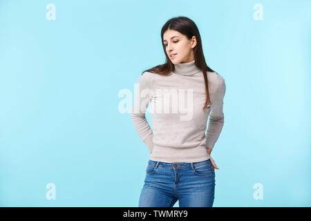 Studio ritratto di una bella donna caucasica, mani sui fianchi, isolato su sfondo blu Foto Stock