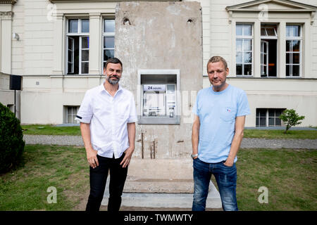 Berlino, Germania. Il 21 giugno, 2019. Michael Elmgreen (r) e Ingar Dragset, insieme i Danish-Norwegian duo di artisti Elmgreen e Dragset, sedersi di fronte al loro scultura 'Statue di liberta' nel cortile di Hamburger Bahnhof. La scultura da 2018 è costituito da un segmento di calcestruzzo del muro di Berlino in cui un functionless cash dispenser è integrato. Il lavoro è stato donato dal collettore Heiner Wemhöner e viene presentato come un permanente di sculture all'aperto. Credito: Christoph Soeder/dpa/Alamy Live News Foto Stock