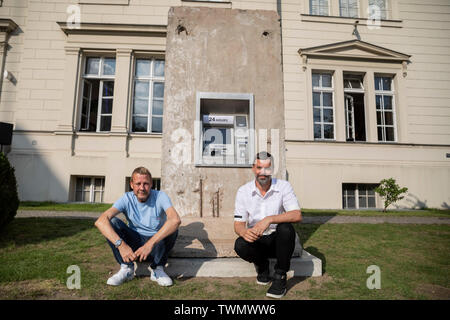 Berlino, Germania. Il 21 giugno, 2019. Michael Elmgreen (l) e Ingar Dragset, insieme i Danish-Norwegian duo di artisti Elmgreen e Dragset, sedersi di fronte al loro scultura 'Statue di liberta' nel cortile di Hamburger Bahnhof. La scultura da 2018 è costituito da un segmento di calcestruzzo del muro di Berlino in cui un functionless cash dispenser è integrato. Il lavoro è stato donato dal collettore Heiner Wemhöner e viene presentato come un permanente di sculture all'aperto. Credito: Christoph Soeder/dpa/Alamy Live News Foto Stock