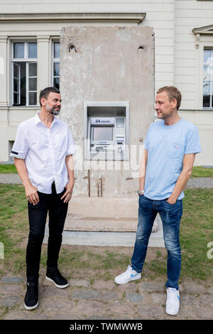 Berlino, Germania. Il 21 giugno, 2019. Michael Elmgreen (r) e Ingar Dragset, insieme i Danish-Norwegian duo di artisti Elmgreen e Dragset, sedersi di fronte al loro scultura 'Statue di liberta' nel cortile di Hamburger Bahnhof. La scultura da 2018 è costituito da un segmento di calcestruzzo del muro di Berlino in cui un functionless cash dispenser è integrato. Il lavoro è stato donato dal collettore Heiner Wemhöner e viene presentato come un permanente di sculture all'aperto. Credito: Christoph Soeder/dpa/Alamy Live News Foto Stock