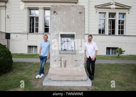 Berlino, Germania. Il 21 giugno, 2019. Michael Elmgreen (l) e Ingar Dragset, insieme i Danish-Norwegian duo di artisti Elmgreen e Dragset, sedersi di fronte al loro scultura 'Statue di liberta' nel cortile di Hamburger Bahnhof. La scultura da 2018 è costituito da un segmento di calcestruzzo del muro di Berlino in cui un functionless cash dispenser è integrato. Il lavoro è stato donato dal collettore Heiner Wemhöner e viene presentato come un permanente di sculture all'aperto. Credito: Christoph Soeder/dpa/Alamy Live News Foto Stock