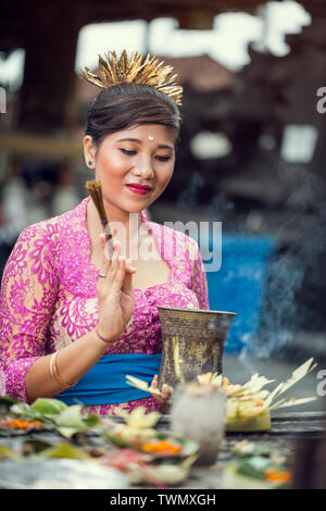 Giovane bella donna asiatica pregando tradizionale abito cerimoniale Foto Stock