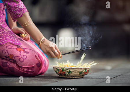 Donna che prega e lascia gli dèi offerte, ogni mattina le donne portano fiori e incenso ai loro dèi Foto Stock