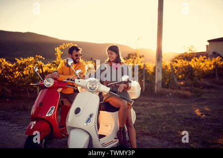 Romantico coppia giovane a cavallo su uno scooter e godendo di viaggio su strada Foto Stock