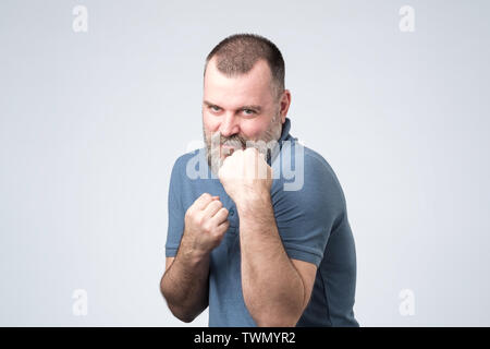 Uomo in camicia blu in piedi in boxer posano con pugno chiuso Foto Stock