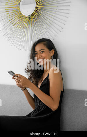 Donna che utilizza il suo telefono cellulare durante una pausa caffè in bianco Coworking Office Foto Stock