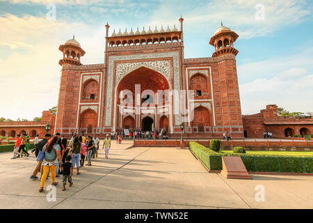 I turisti nella parte anteriore del Taj Mahal di East gate realizzata in pietra arenaria rossa con marmo bianco incisioni a Agra, India Foto Stock