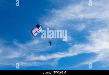 Il parasailing o parascending o para il kite, Ricreativo Attività kite, volare nel cielo blu chiaro. In Patong Beach, Phuket, Tailandia. Foto Stock