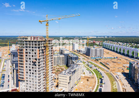 Sito in costruzione con highrise building e gru sul cielo azzurro sfondo. nuova zona residenziale. Vista aerea Foto Stock