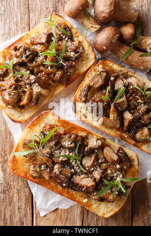 Deliziosa la ciabatta fritto con funghi porcini, cipolle, il timo e il formaggio parmigiano reggiano closeup sul tavolo. Verticale in alto vista da sopra Foto Stock
