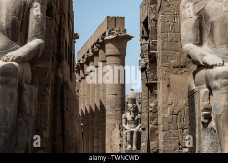 Egitto Tempio di Luxor. statua in granito di Ramesse II seduto di fronte a colonne. Foto Stock