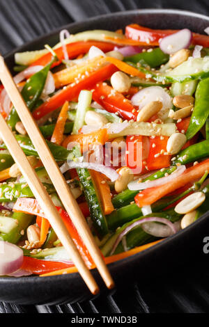 Vegetariano insalata di verdure con sesamo e arachidi close-up su una piastra sul piano verticale. Foto Stock
