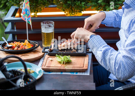 La birra. Concetto di pranzo,con grigliate di carne, insalata di patate. Imprenditore a pranzo in una strada o un ristorante all'aperto. Foto Stock