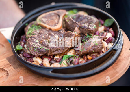 Servire grigliate di carne di manzo con fagioli close-up su una piastra su un tavolo. Concetto di ristorante Foto Stock