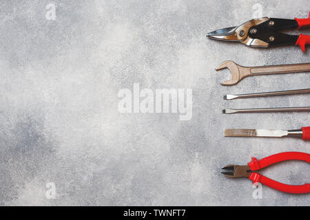 Pinze, cacciaviti e chiavi a combinazione di cemento grigio Sfondo con copia spazio. Professional ergonomica degli strumenti di riparazione Foto Stock