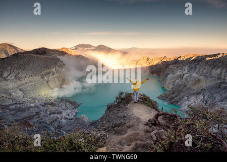 Uomo in piedi sul crinale del cratere a sunrise mattina. Kawah Ijen vulcano, East Java, Indonesia Foto Stock