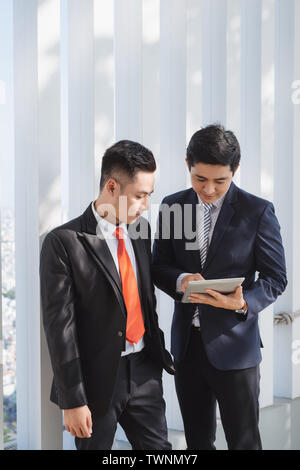 Due maschi vietnamita i colleghi a parlare e sorridente Foto Stock