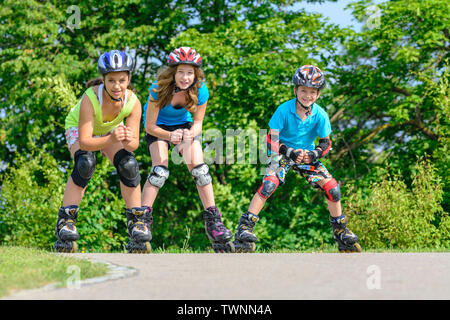 Tre giovani adolescenti in un divertente tour con pattini a rotelle in posizione di parcheggio Foto Stock