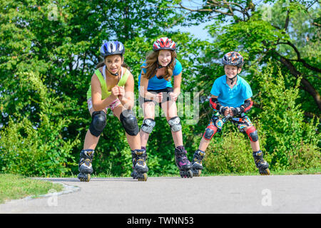 Tre giovani adolescenti in un divertente tour con pattini a rotelle in posizione di parcheggio Foto Stock