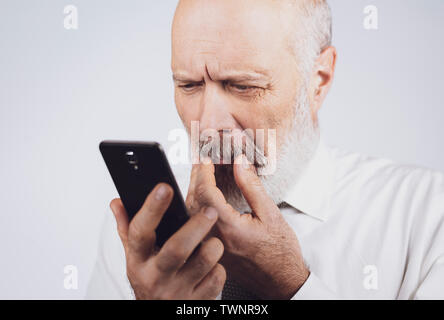 Senior uomo utilizzando le applicazioni sullo smartphone, egli sta avendo difficoltà e problemi di visione Foto Stock