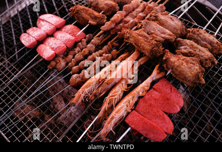 Cuocere carne e gamberi tappati con il bastone di metallo sul vassoio Foto Stock